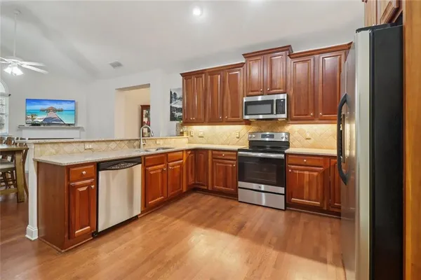 a kitchen with stainless steel appliances granite countertop a sink and a stove with wooden floor