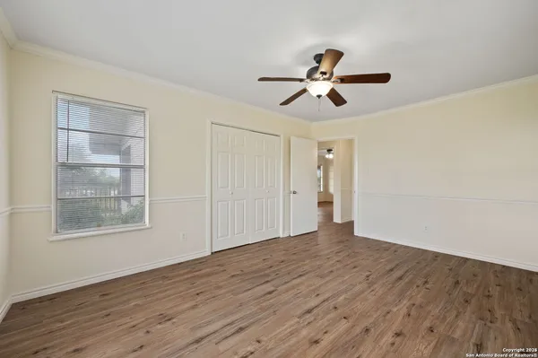 a view of empty room with wooden floor and ceiling fan