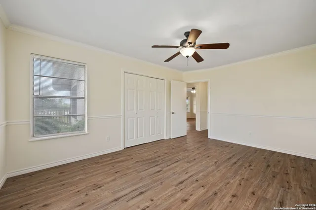 a view of empty room with wooden floor and ceiling fan