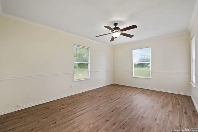 a view of empty room with wooden floor and fan