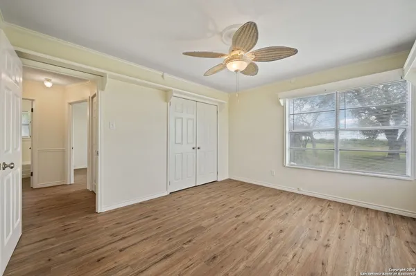 a view of empty room with wooden floor and fan