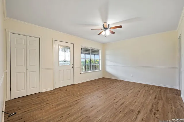 a view of empty room with wooden floor and fan