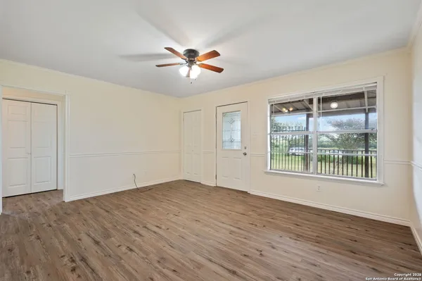 a view of an empty room with wooden floor and a window