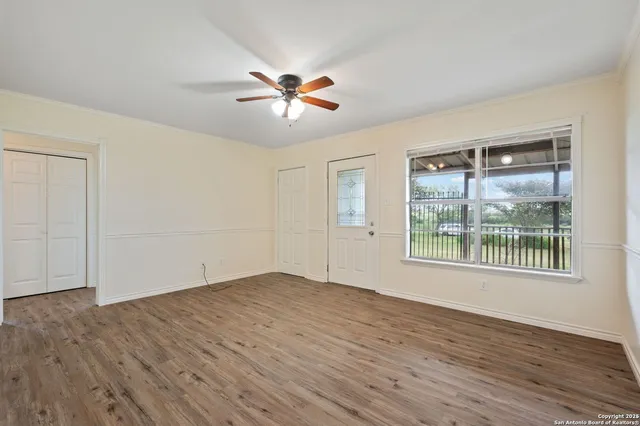 a view of an empty room with wooden floor and a window