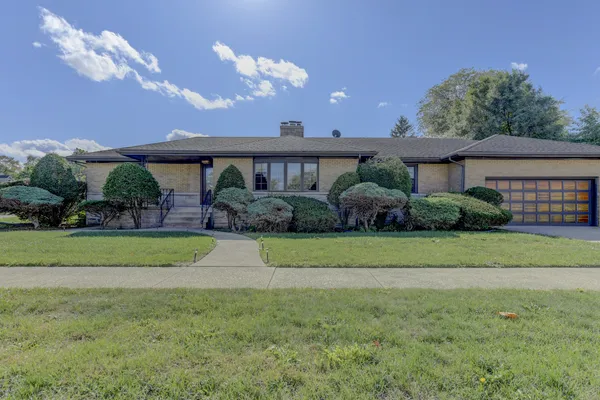 a front view of a house with a yard and potted plants