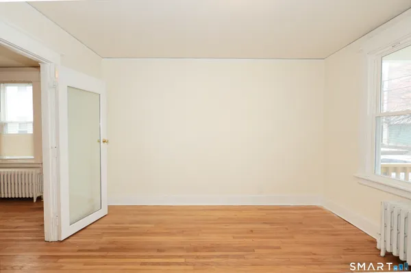 an empty room with wooden floor and windows with curtains