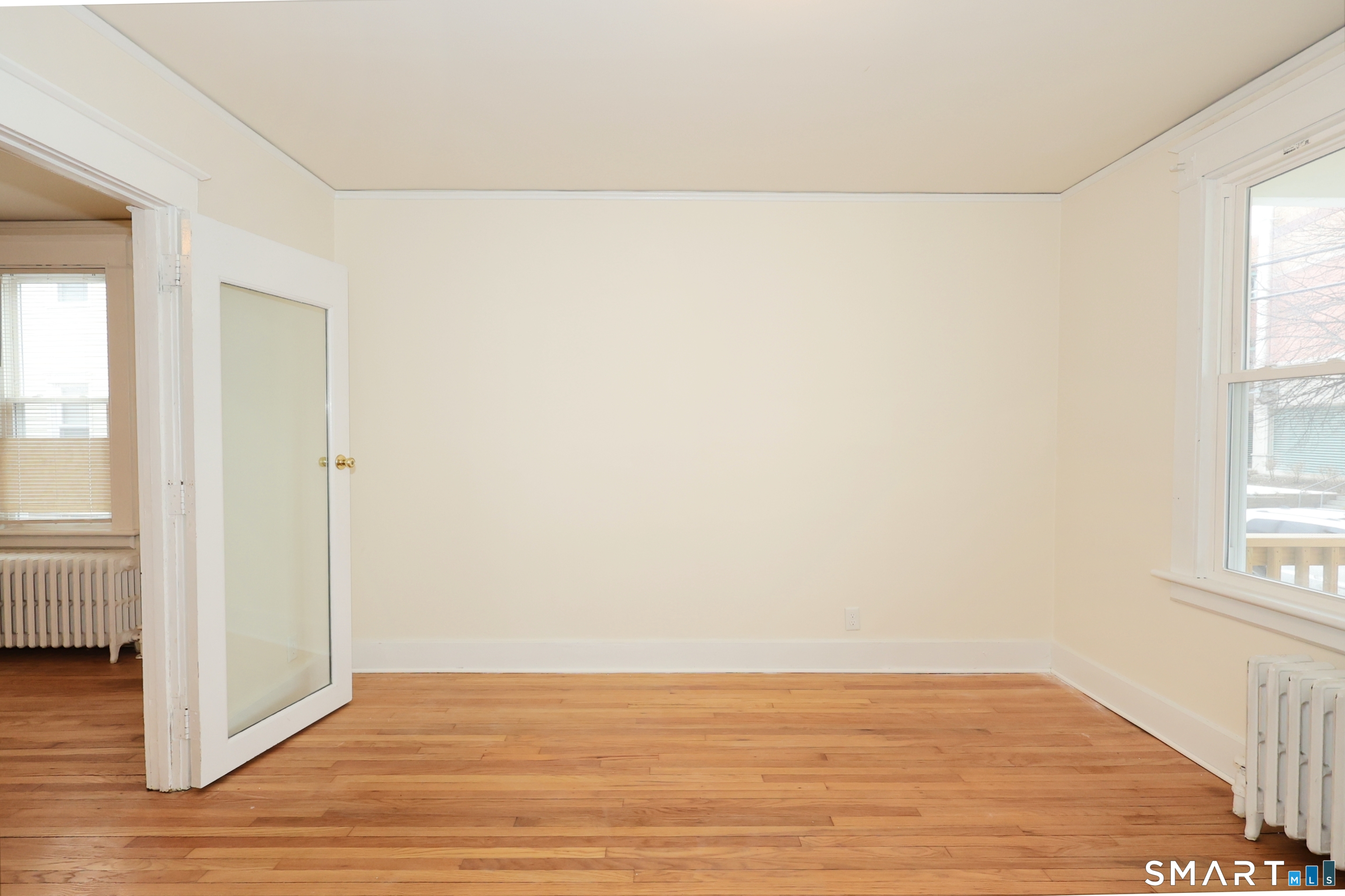 146 Division Street, Unit 1 Ansonia, CT 06401 - Photo 9 of 27 an empty room with wooden floor and windows with curtains