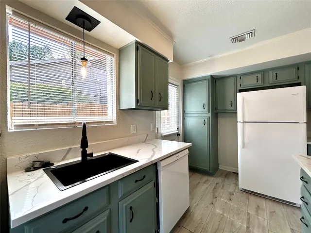 a kitchen with a sink a refrigerator and cabinets
