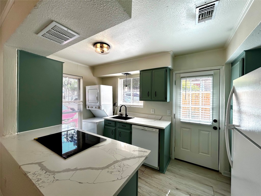 1005 West Martin Luther King Jr Boulevard, Unit B Austin, TX 78701 - Photo 8 of 29 a kitchen with stainless steel appliances kitchen island granite countertop a sink and dishwasher a stove with wooden floor