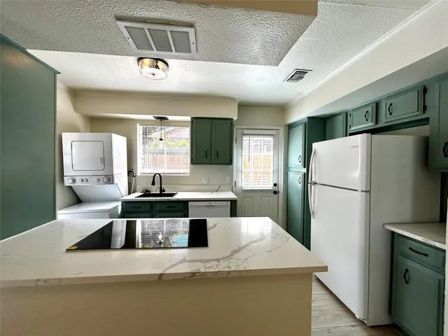 a kitchen with stainless steel appliances granite countertop a refrigerator a sink a stove and a refrigerator