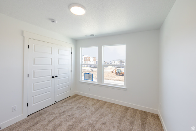4809 Olive Avenue, Unit 417 Mapleton, UT 84664 - Photo 14 of 18 Unfurnished bedroom with a closet, light colored carpet, and a textured ceiling