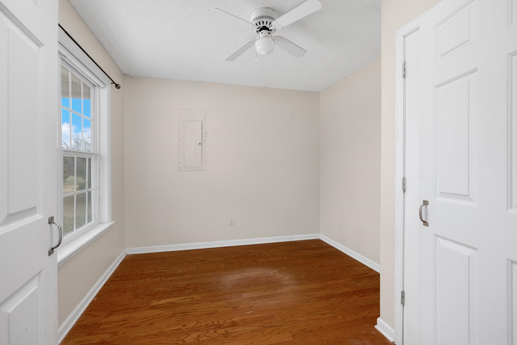 275 Morris Road Covington, TN 38019 - Photo 6 of 32 Empty room with wood-type flooring, electric panel, and ceiling fan