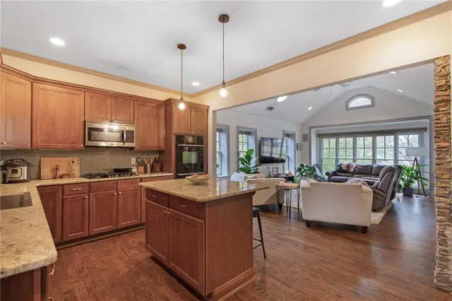 a large kitchen with kitchen island a stove a sink a dining table and chairs with wooden floor