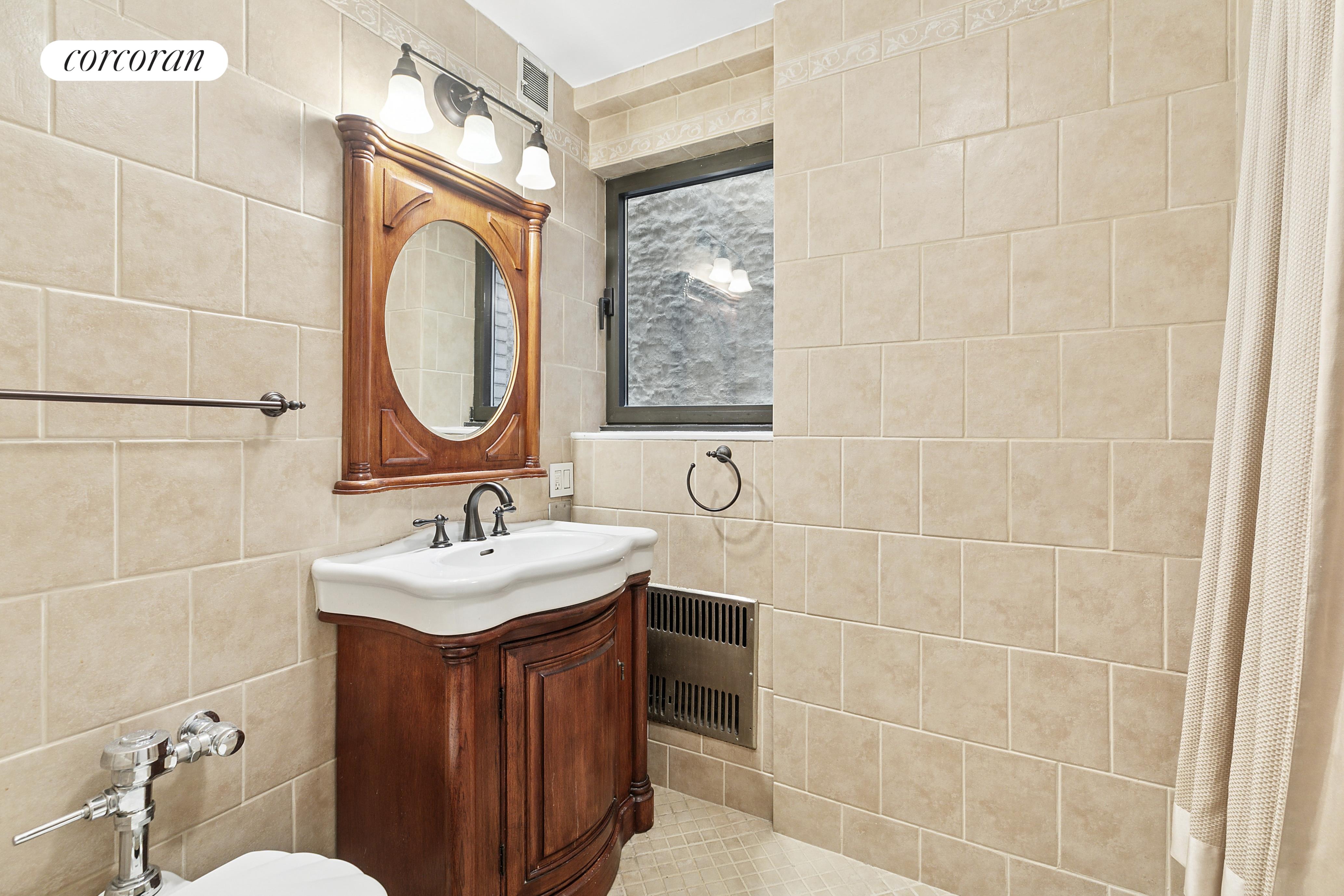 25 East 83rd Street, Unit 2E Manhattan, NY 10028 - Photo 18 of 19 a bathroom with a sink a toilet and mirror