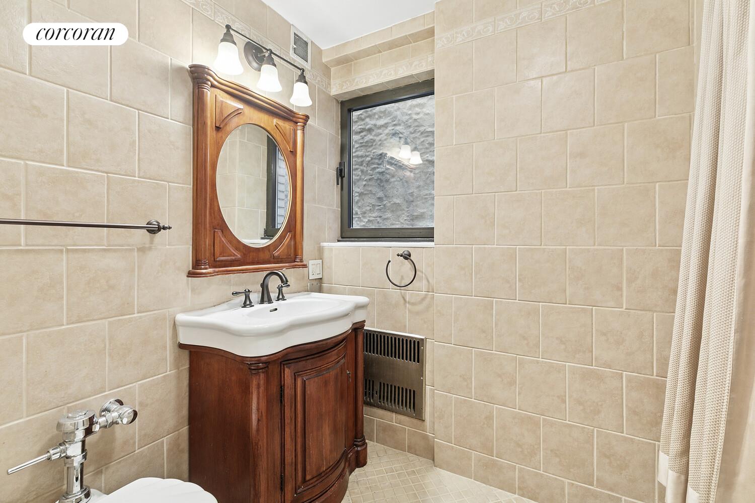 25 East 83rd Street, Unit 2E Manhattan, NY 10028 - Photo 7 of 19 a bathroom with a sink a toilet and mirror