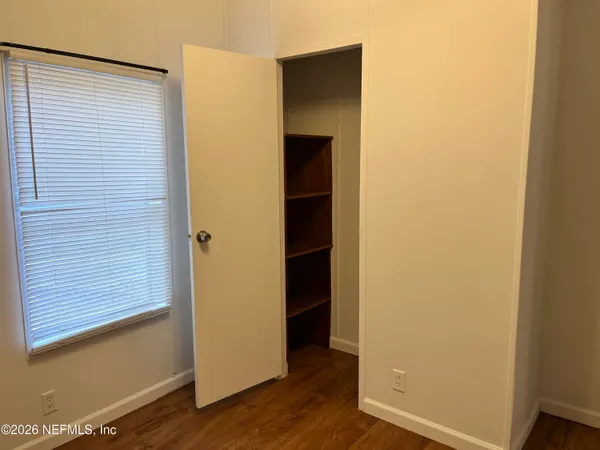 a view of an empty room with wooden floor and closet