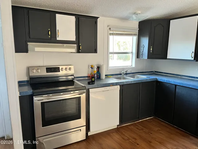 a kitchen with granite countertop cabinets stainless steel appliances and wooden floor