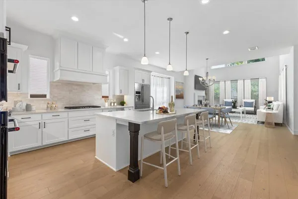 a kitchen with stainless steel appliances kitchen island granite countertop a stove a sink a island with a dining table and chairs