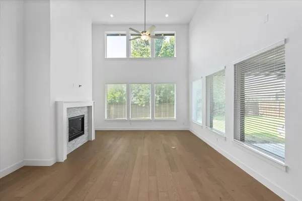 an empty room with wooden floor fireplace and windows