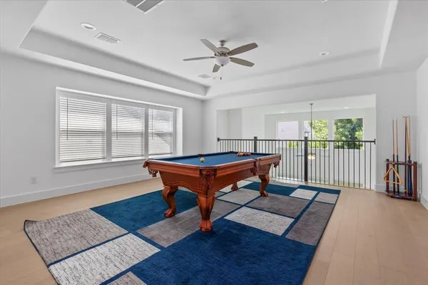 a room with wooden floor pool table and windows