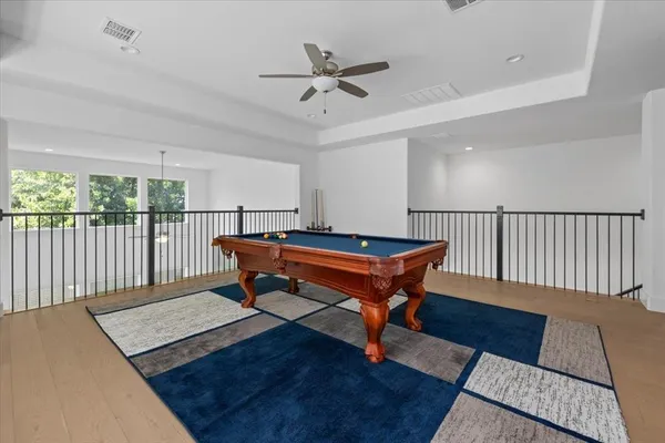 a room with wooden floor pool table and windows