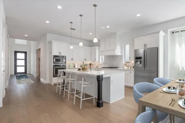 a kitchen with a dining table chairs refrigerator and microwave