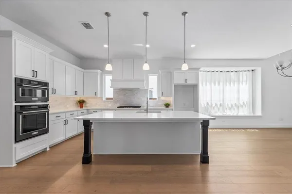 a kitchen with kitchen island a counter top space a sink stainless steel appliances and cabinets
