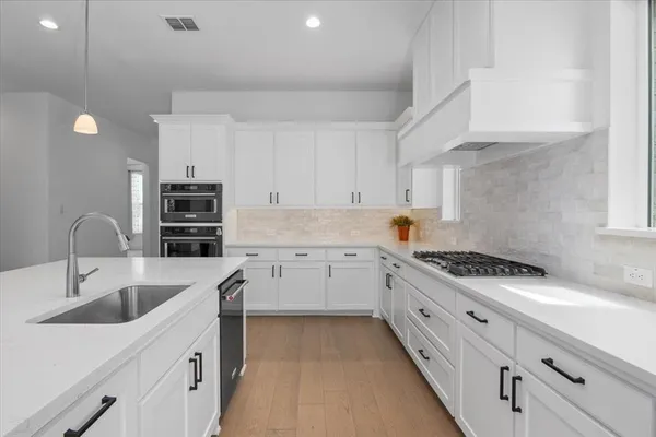a kitchen with granite countertop a sink stainless steel appliances and cabinets