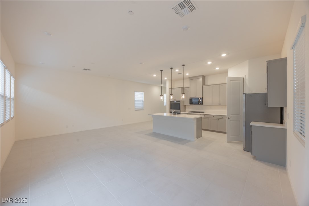 95 Silver Run Lane Las Vegas, NV 89138 - Photo 18 of 18 Kitchen with open floor plan, gray cabinetry, hanging light fixtures, a center island with sink, and appliances with stainless steel finishes