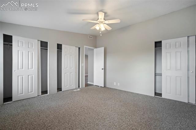 20150 Enoch Road Colorado Springs, CO 80928 - Photo 26 of 50 Unfurnished bedroom featuring two closets, carpet flooring, and a ceiling fan