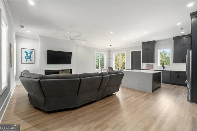 a living room with couches a flat screen tv and kitchen view