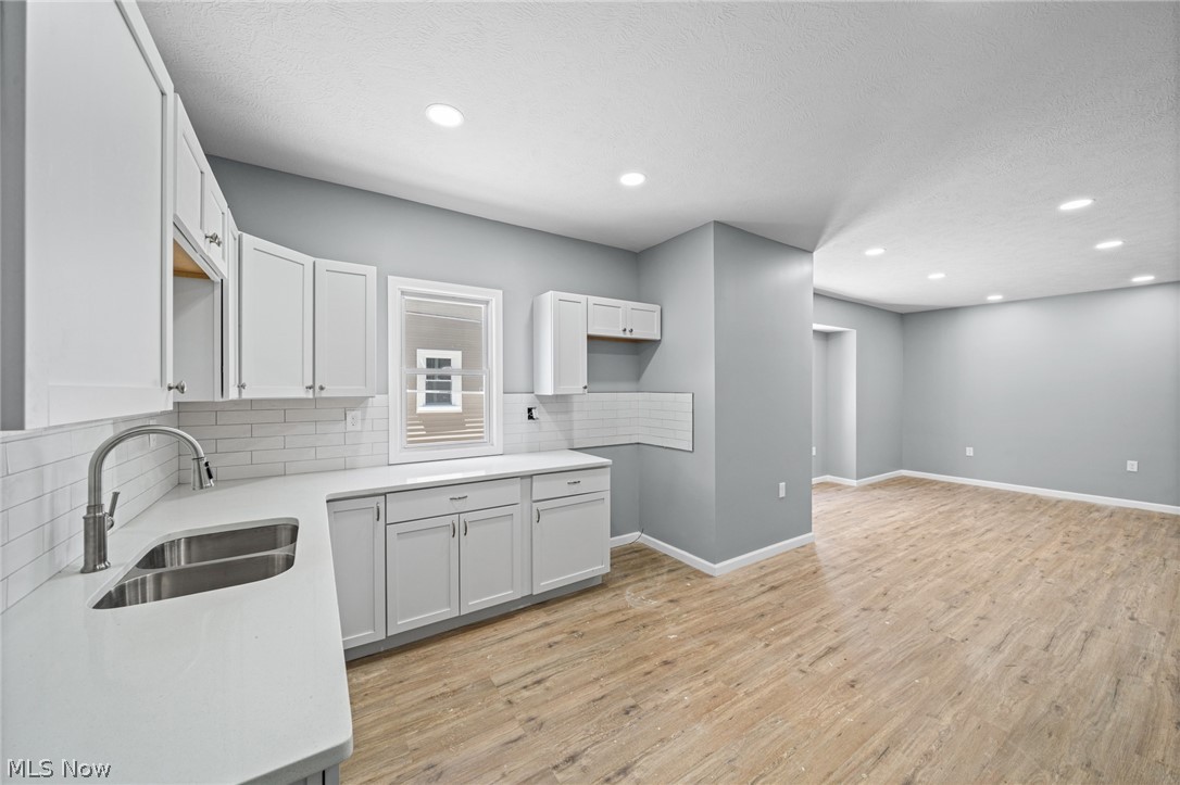 3925 Riverside Avenue Cleveland, OH 44109 - Photo 12 of 48 Contemporary kitchen featuring white cabinetry, a double basin stainless steel sink, white subway tile backsplash, and light-toned wood-finish flooring