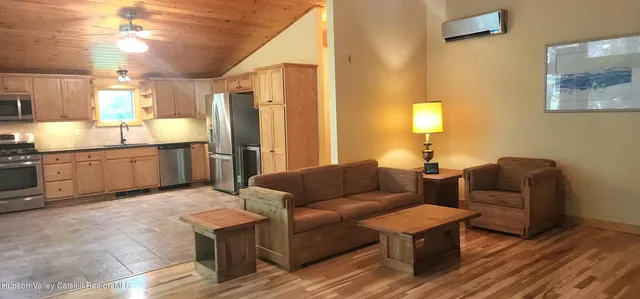 a living room with stainless steel appliances granite countertop furniture a fireplace and a chandelier