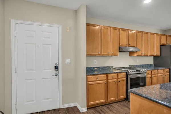 a kitchen with stainless steel appliances granite countertop white cabinets and a stove top oven