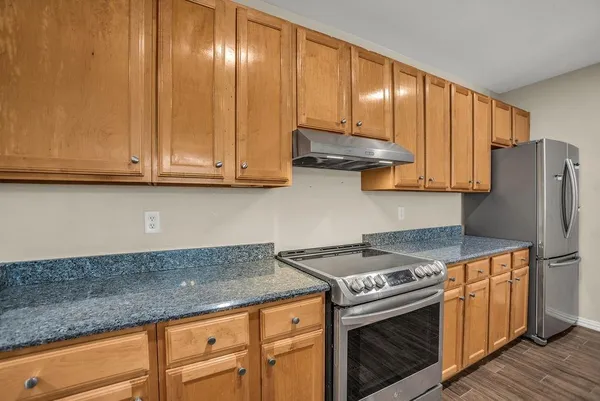 a kitchen with granite countertop cabinets stainless steel appliances and wooden floor