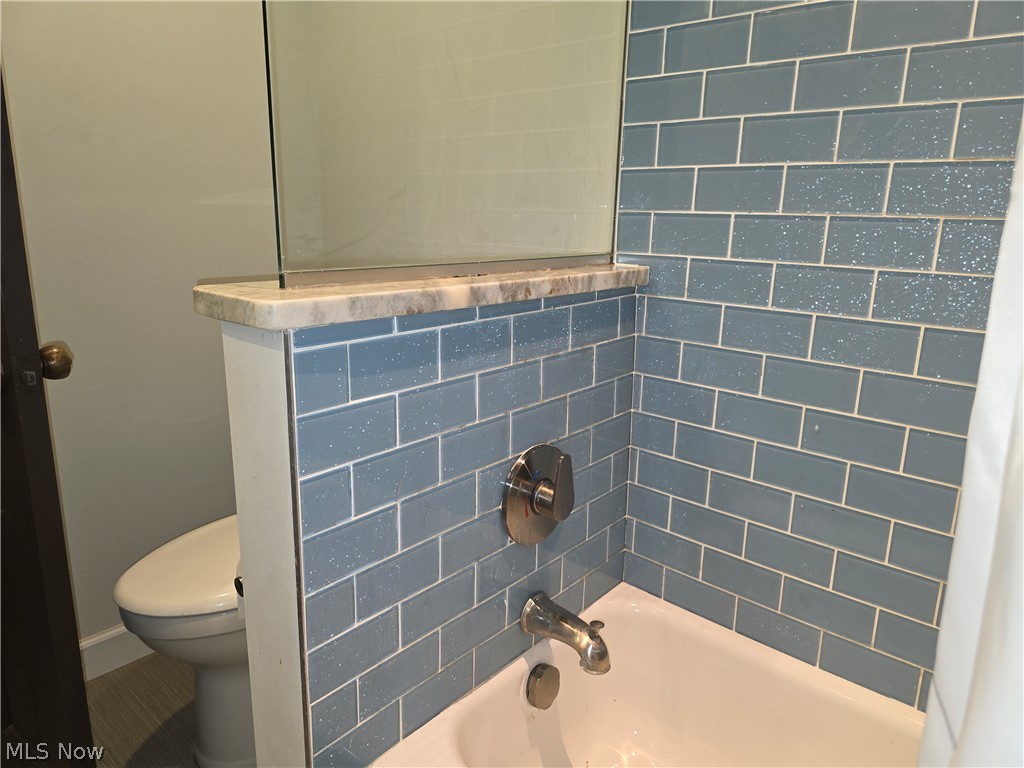 2868 Shade Road Akron, OH 44333 - Photo 35 of 49 Bathroom featuring blue subway tile surround, white bathtub, and brushed nickel fixtures