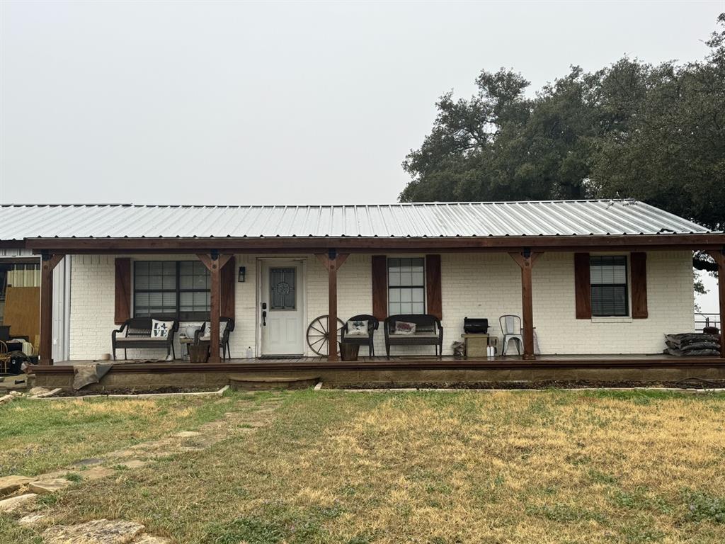 View of front facade featuring covered porch, metal roof, a front porch, and brick siding