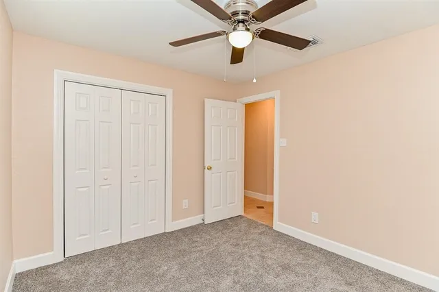 an empty room with closet and a chandelier fan