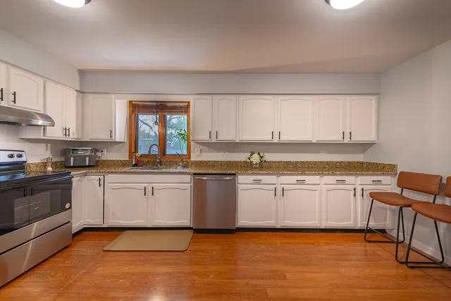 a kitchen with stainless steel appliances granite countertop a stove a sink and a microwave