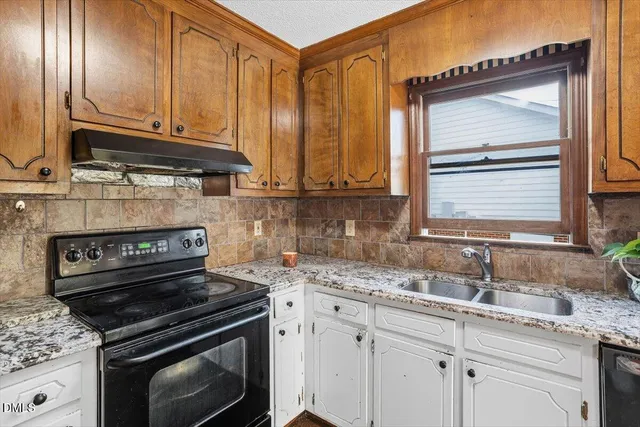 a kitchen with granite countertop a stove sink and cabinets