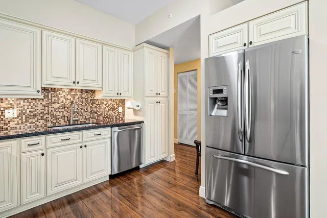 a kitchen with granite countertop stainless steel appliances a refrigerator and cabinets