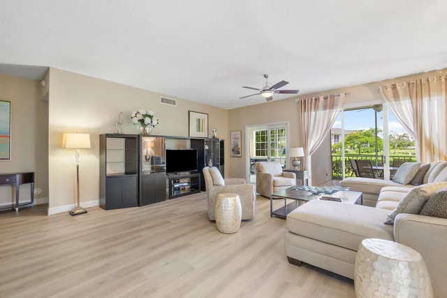 a living room with furniture a large window and a wooden floor