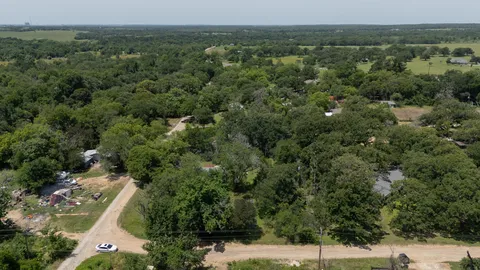 an aerial view of residential houses with outdoor space and trees