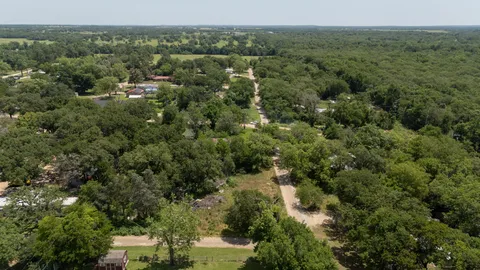 an aerial view of residential houses with outdoor space and trees