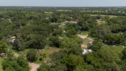 an aerial view of residential houses with outdoor space and trees