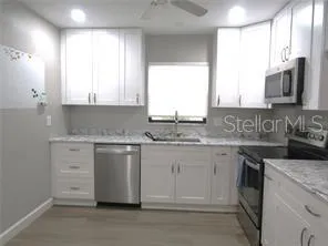 a kitchen with granite countertop white cabinets and a sink