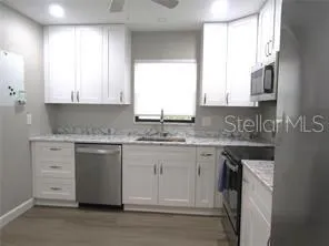 a kitchen with granite countertop white cabinets and a sink