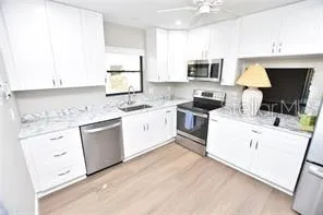 a kitchen with granite countertop a sink stainless steel appliances and white cabinets