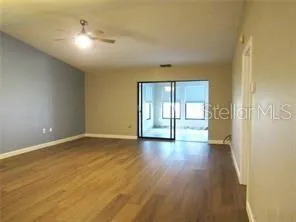 a view of an empty room with wooden floor and a window