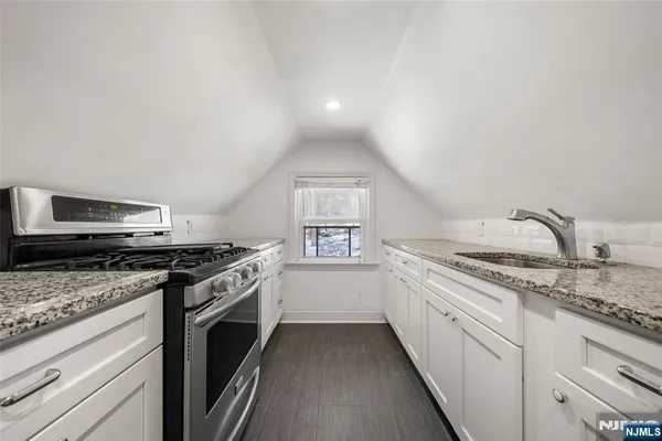 a kitchen with granite countertop a stove sink and cabinets